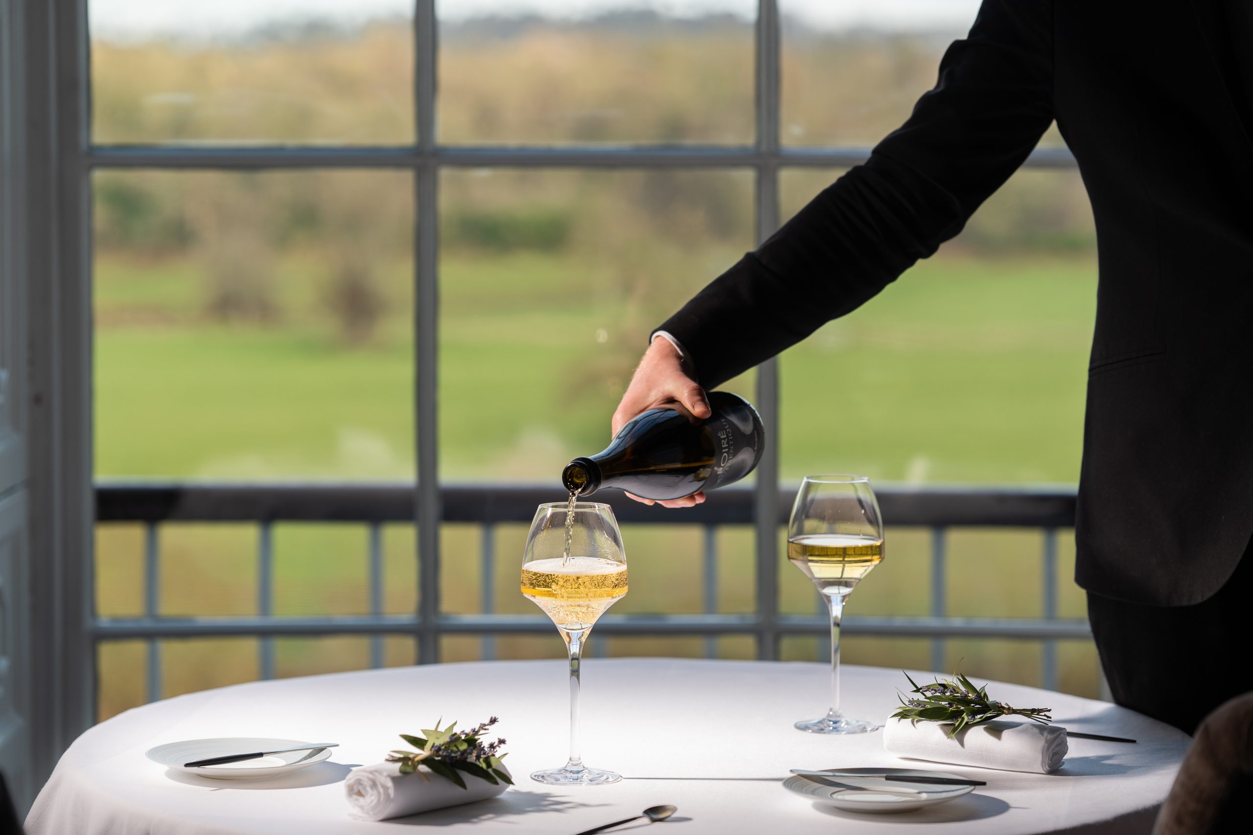 Wine being poured into glasses at window table